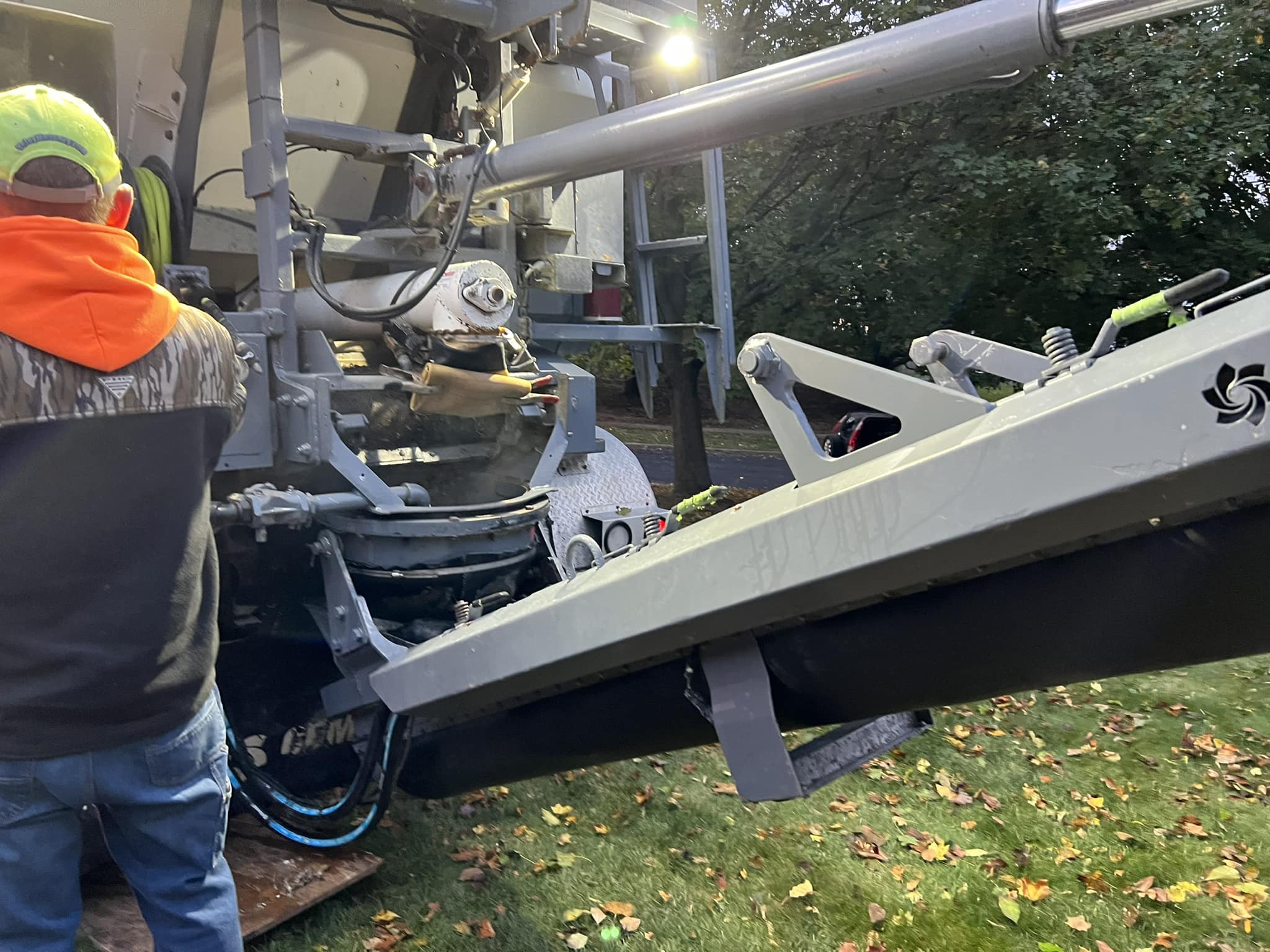 Worker operating concrete boom pump truck with extended arm on residential jobsite