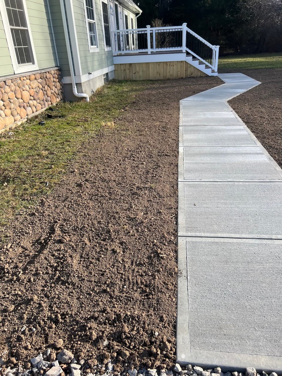 Newly poured concrete walkway leading to elevated deck with stairs