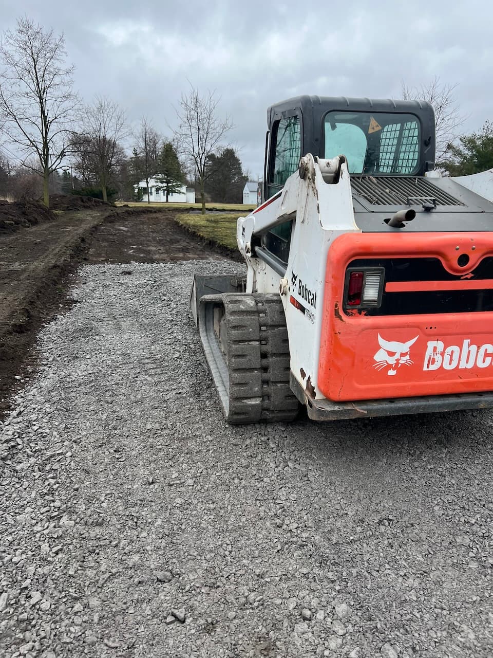 Bobcat compact track loader on gravel driveway during excavation work