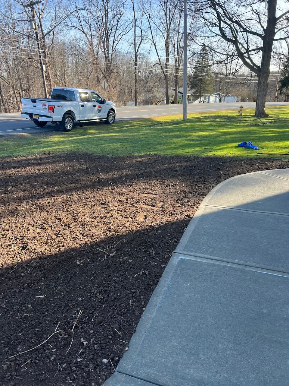 Newly installed curved concrete sidewalk with prepared ground and work truck