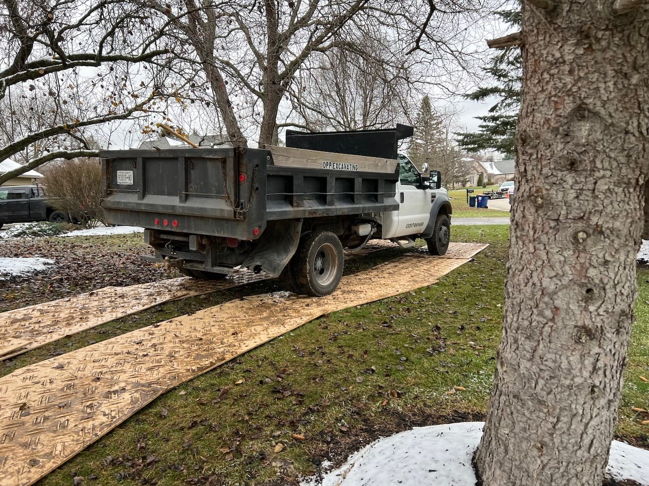 White dump truck with excavation equipment on metal ground protection mats