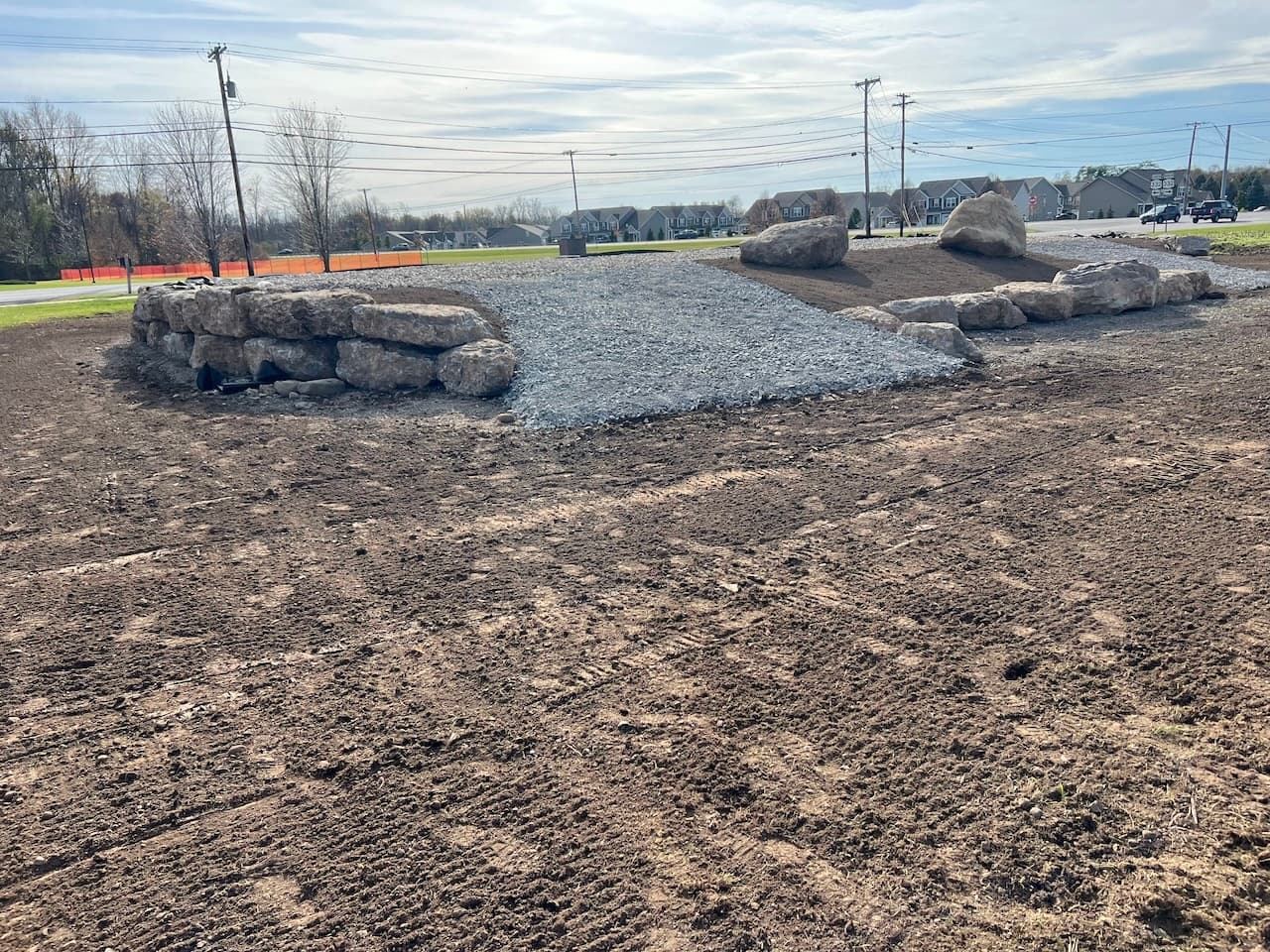 Gravel base layer with large decorative boulders for residential driveway construction