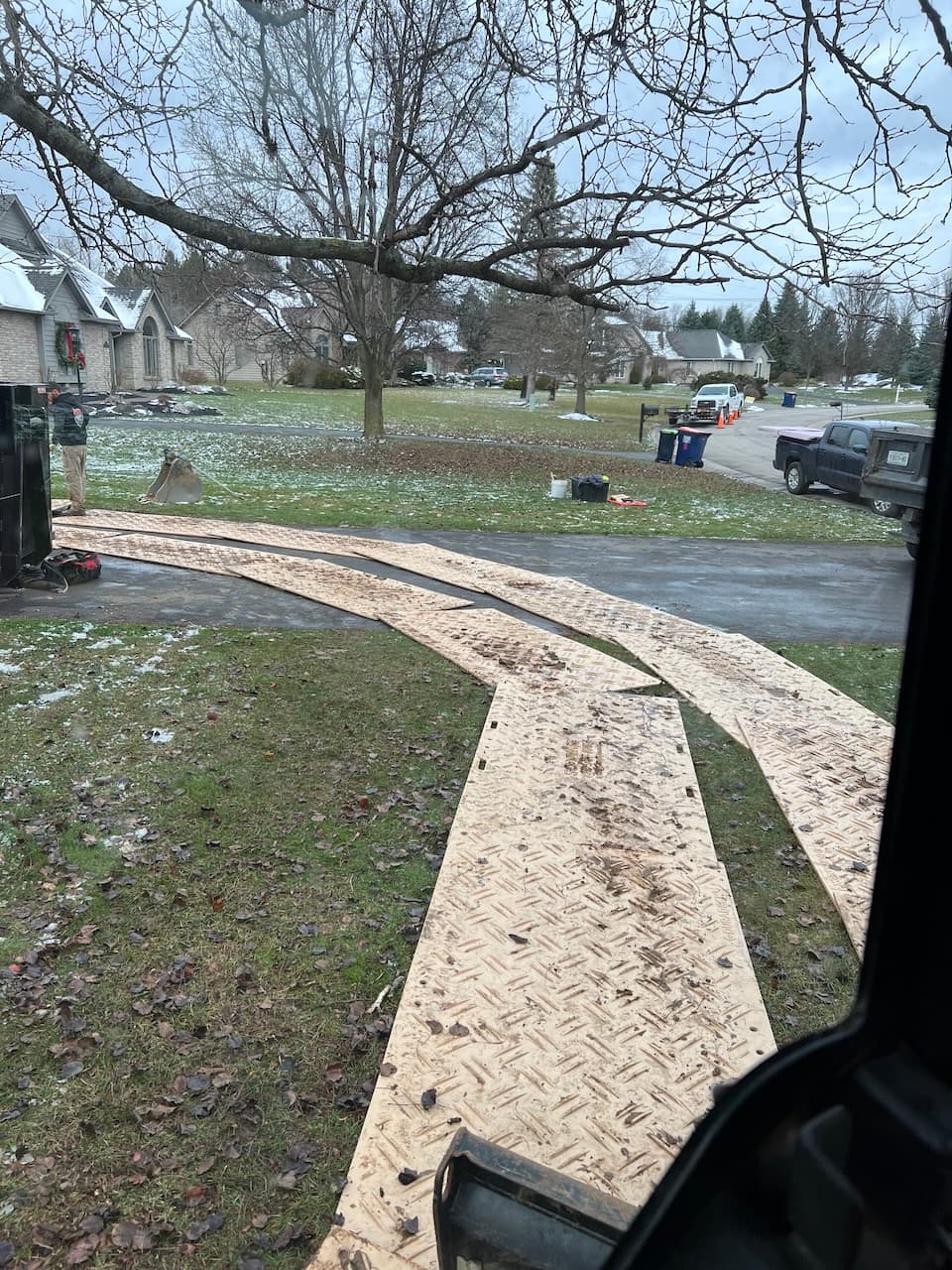 Plywood ground protection mats laid over lawn and driveway during excavation work