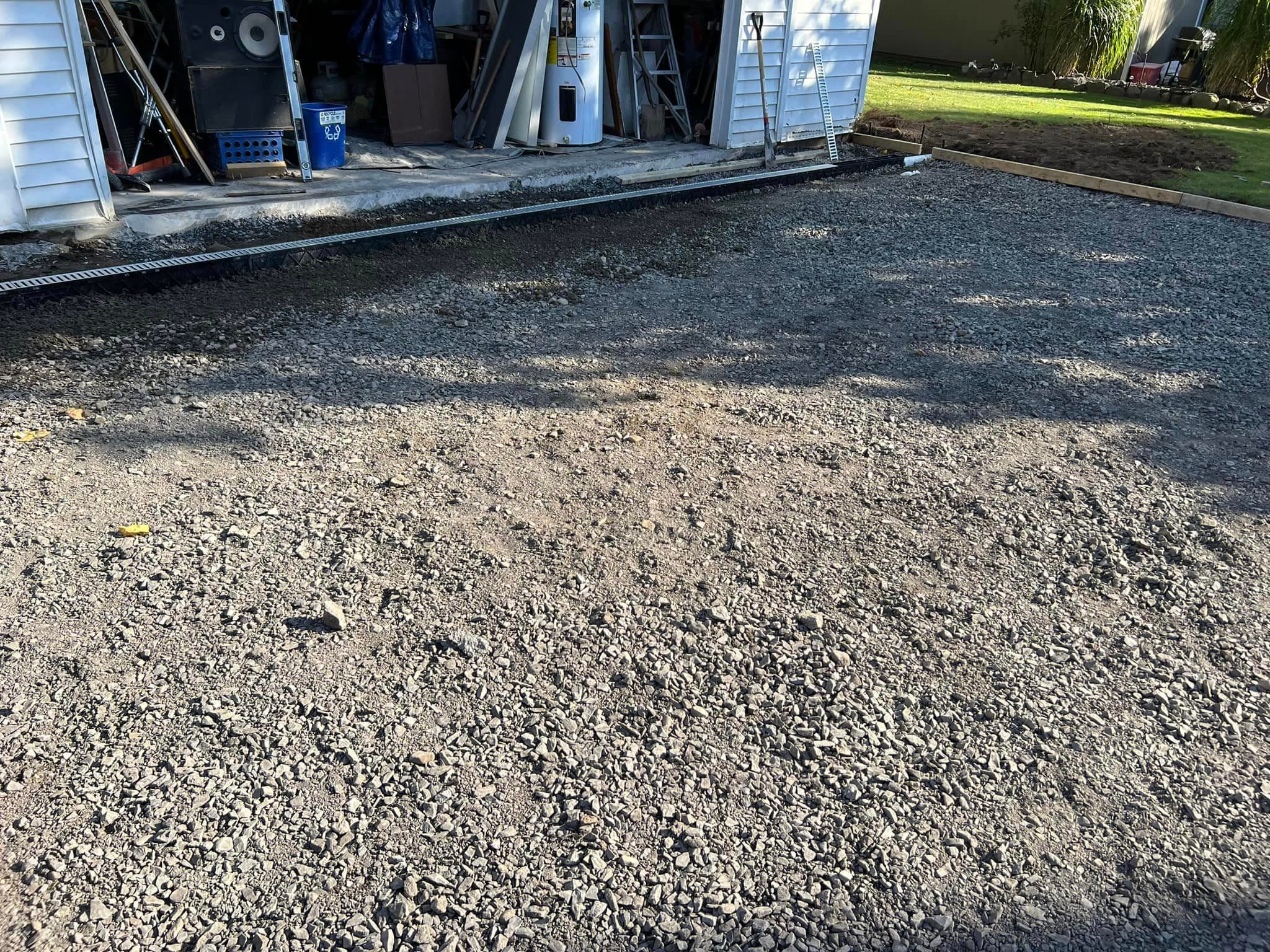 Gravel base layer prepared for asphalt paving near garage entrance