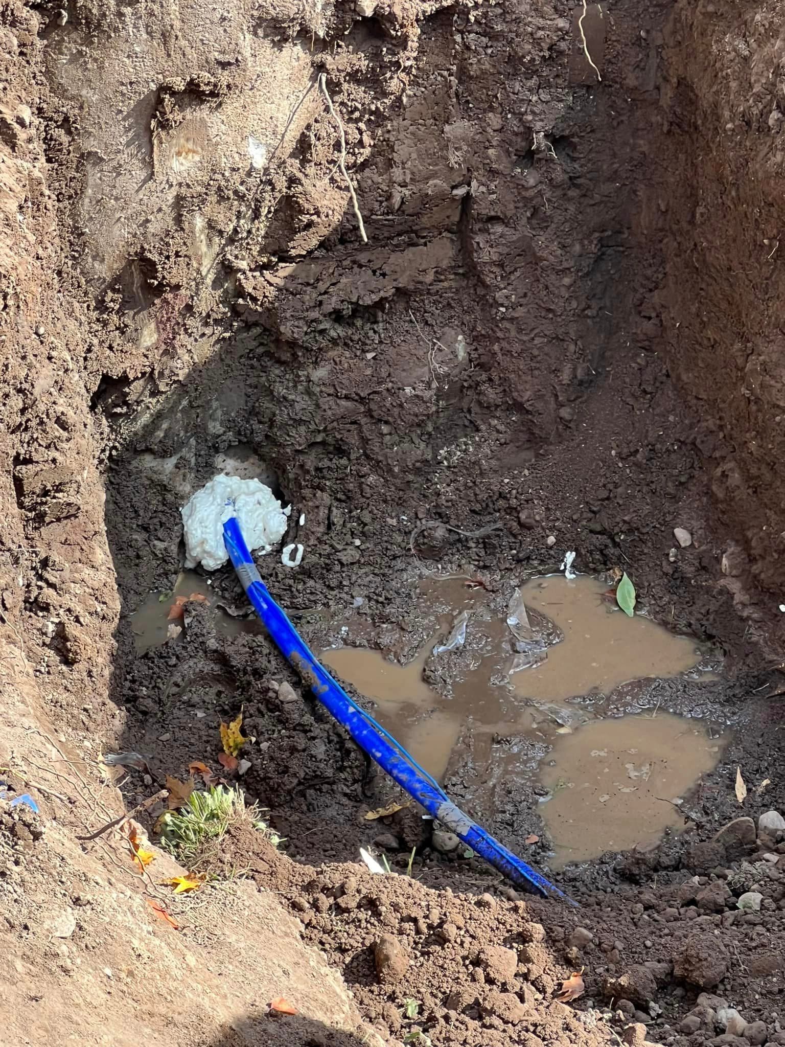 Excavation trench with blue drainage pipe and standing water at job site